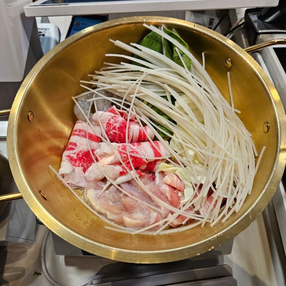 A Big Way pot of beef, chicken, shrimp, cabbage, greens and a mountain of rice noodles, sitting on the scale at the counter