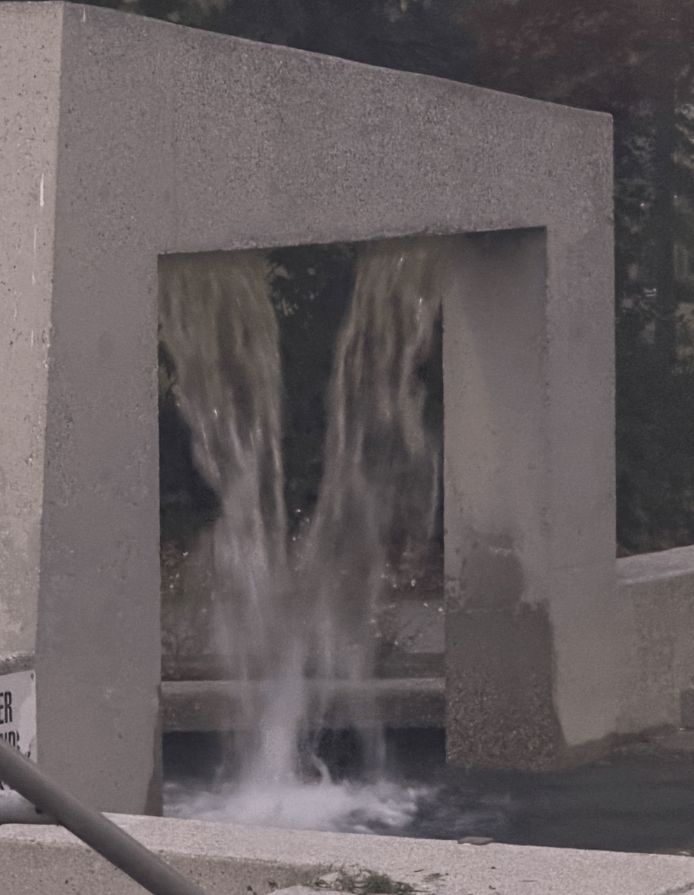 Water pouring through a square opening in a concrete wall